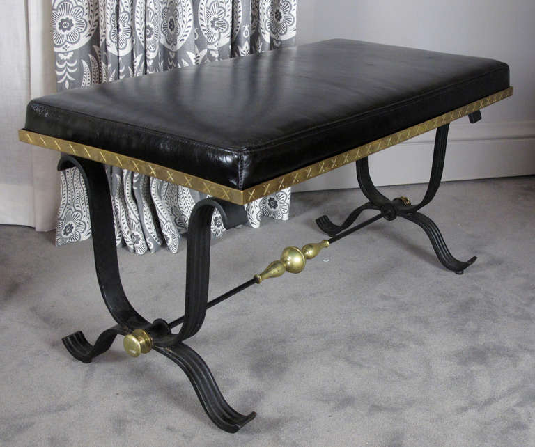 This is a very decorative and nicely made pair of Mid-Century benches. Constructed of heavy iron with brass accents, the pair has been newly upholstered in a supple glazed black leather.