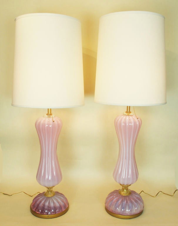 An impressive and large pair of pink opalescent Murano glass lamps, attributed to Seguso.  Nice accents of clear glass with gold inclusions.  The glass portion alone measures approximately 23 inches.  To the top of the shades as shown, they measure