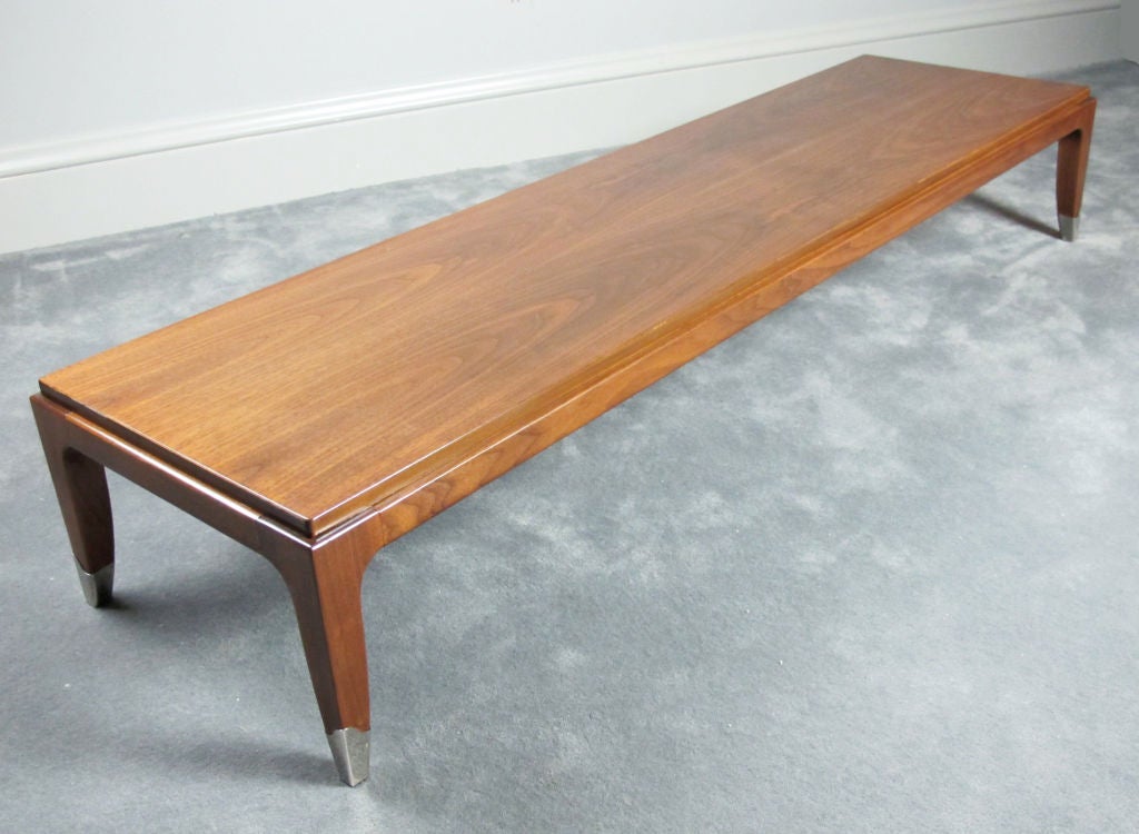 Sexy, long, low walnut coffee table with saber legs and applied polished steel sabots.