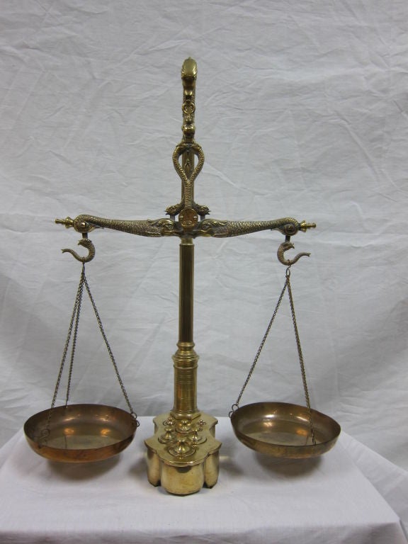 Maco Braga brass balance beam scale with reeded column standard with sea serpent termination, dolphin shaped balance beam and base fitted with complete set of weights.<br />
CA 1880-90
