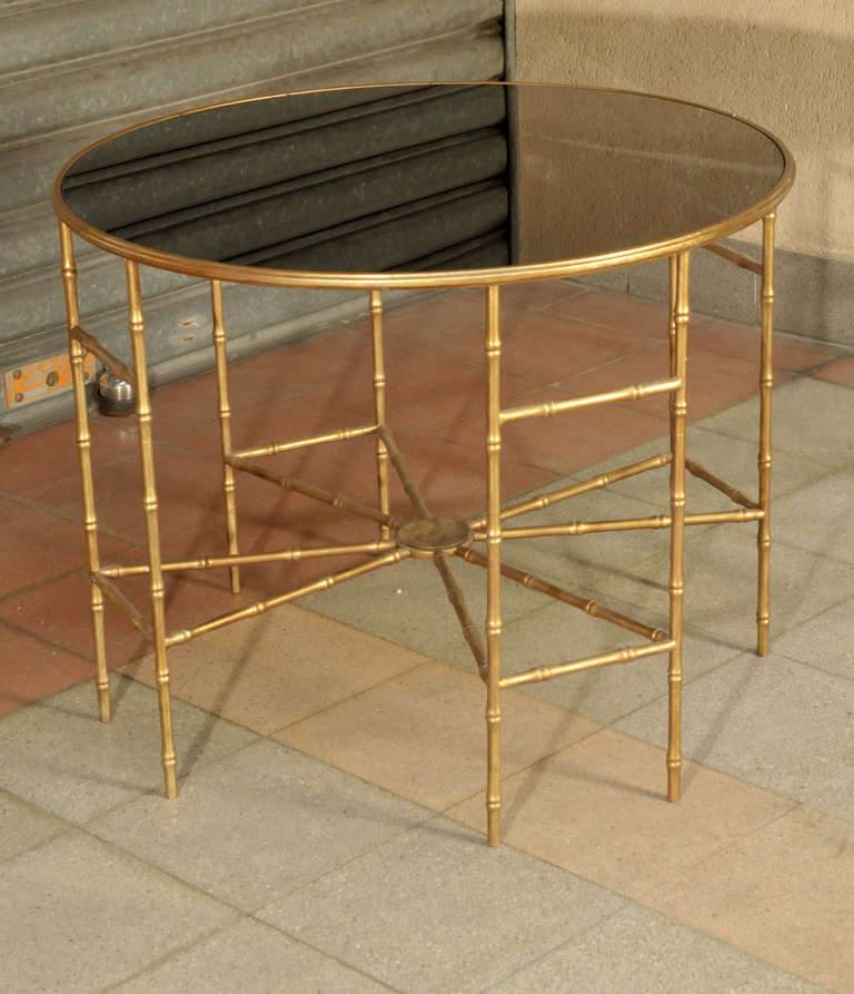 Pedestal table in bamboo metal and black glass on the top.