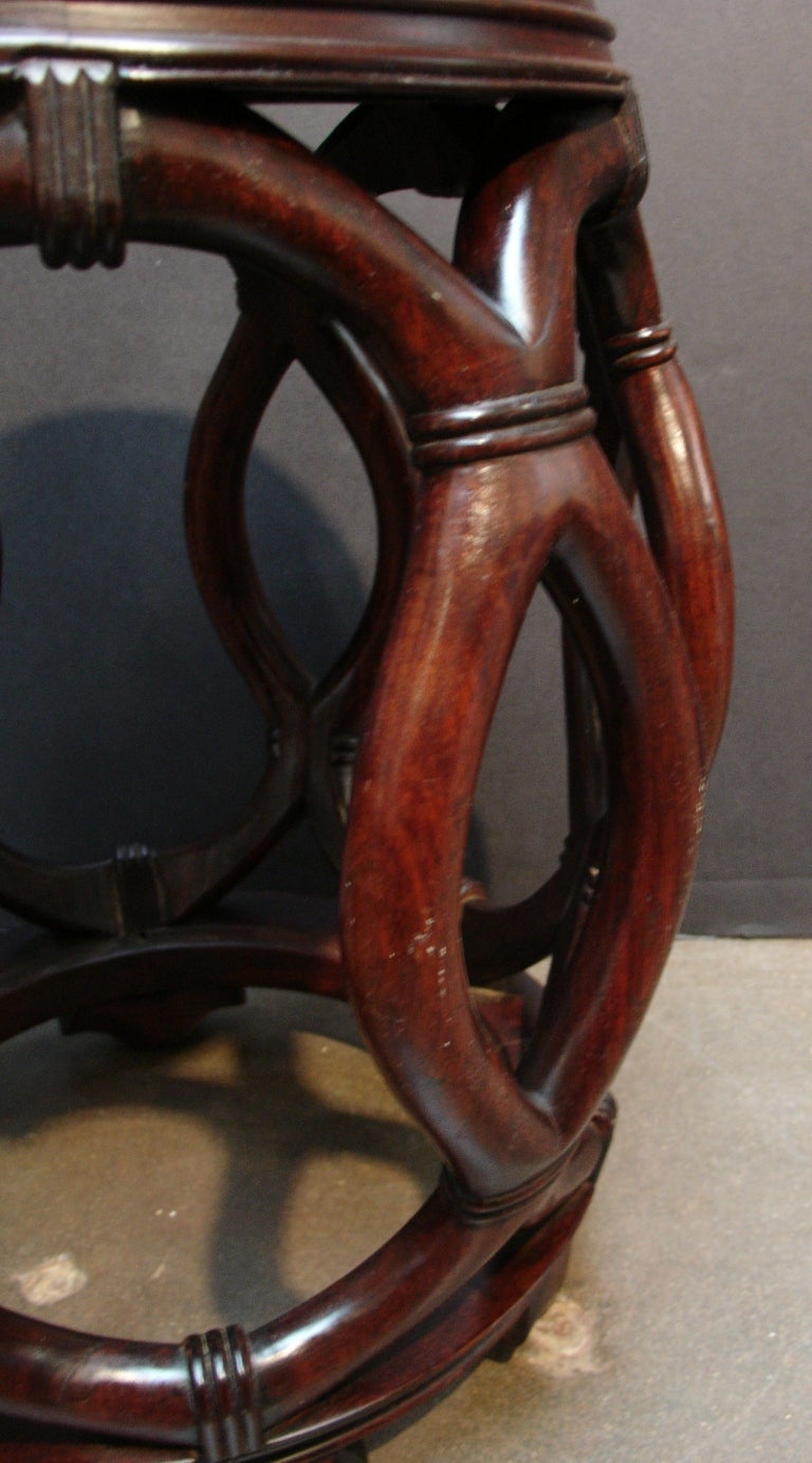 A Chinese carved hardwood drum stool. 

The simple, elegant form is highlighted by the carved, interlaced open sides supporting a solid, inset seat. 

The wood displays a rich, dark patina and an attractive grain.