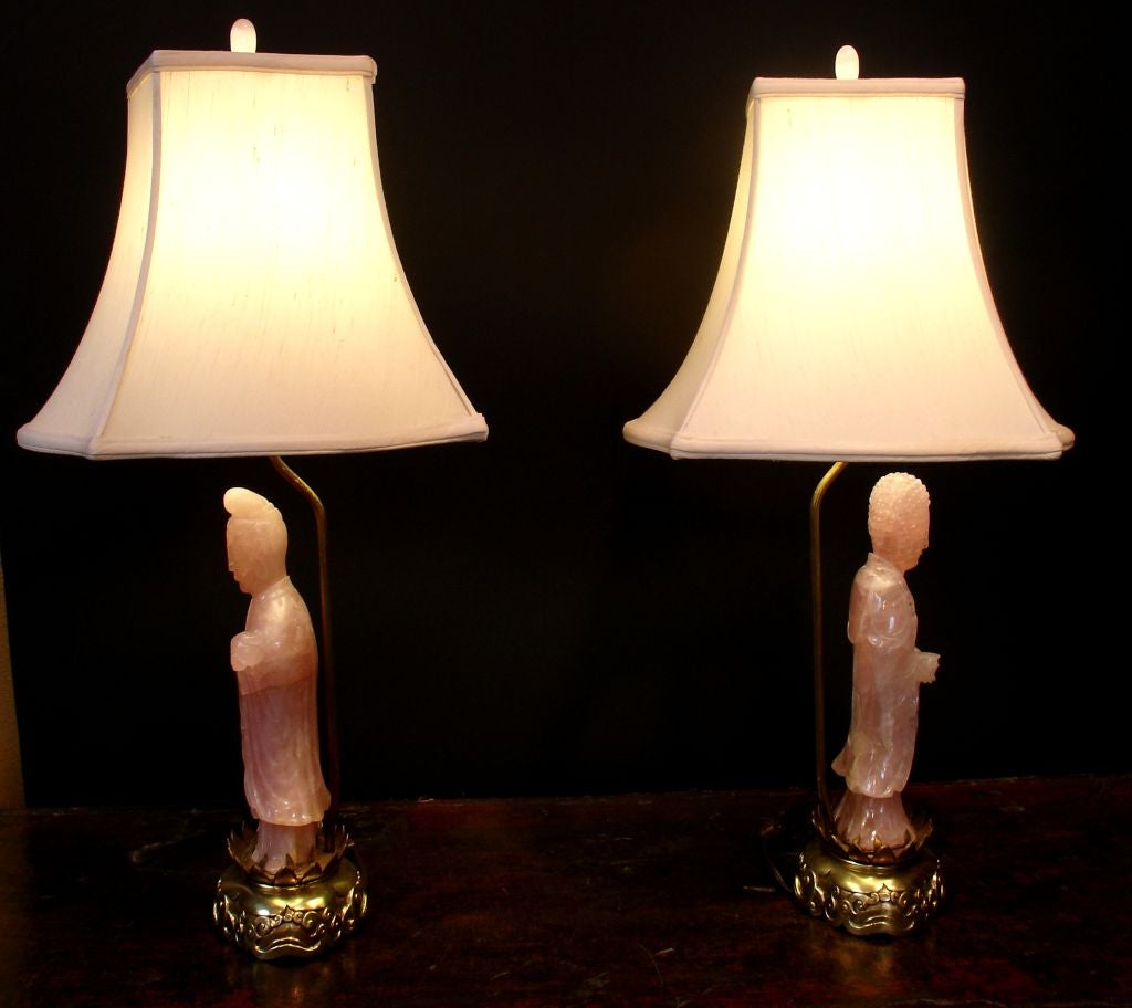 A pair of finely carved rose quartz figures, one as Buddha holding an alms bowl, the other as Guanyin holding a ruyi scepter, now mounted as lamps.