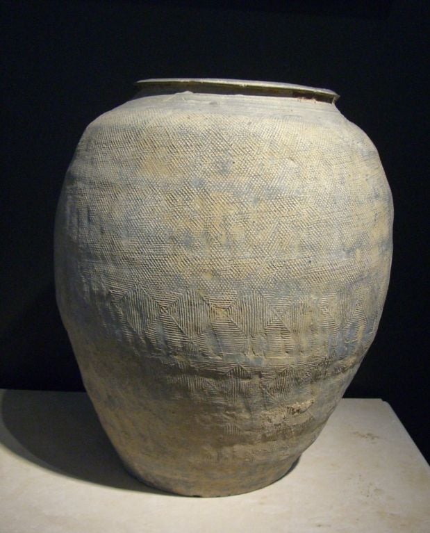 A large storage jar of slightly irregular shape. Wonderful buff gray pottery with areas of lighter coloring. Impressed designs cover the body and shoulders (see detail photos). A slightly everted rim.