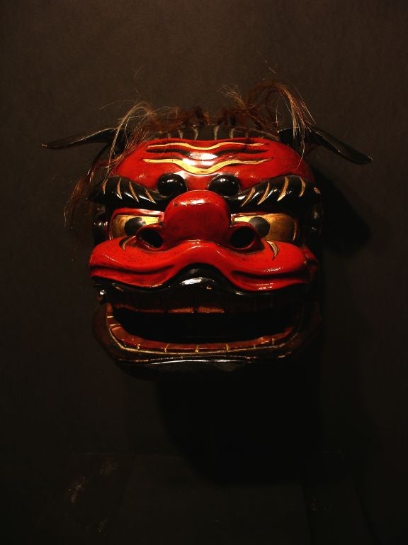A charming Japanese mask originally used in traditional lion dances (shishimai)to scare away evil spirits and usher in good luck. This mask features an articulated mouth, tongue, and ears. Horse hair has been used to simulate a mane. <br />
<br