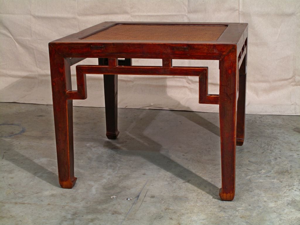 A well-constructed Chinese square side table of elmwood. Clean and simple lines, with minimal decoration. The apron, with a geometric design reminiscent of a simple Greek key pattern, can actually be interpreted as abstracted facing dragons. The