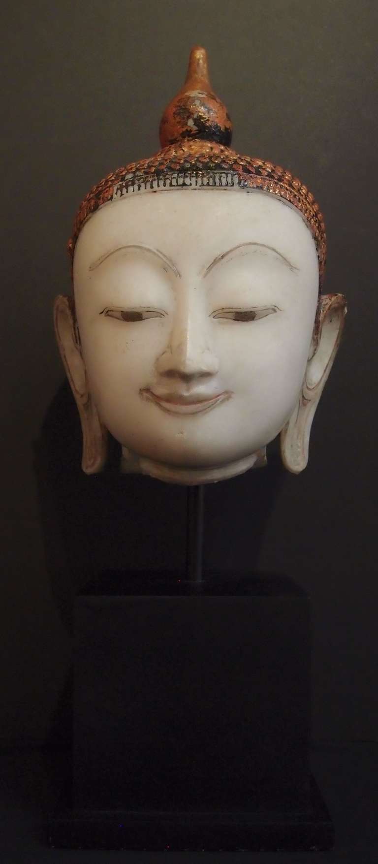 A life size marble head of the Buddha from the Shan States of Burma.  Carved from a single block of white marble, the Buddha's round, moon like face features high, arched brows, a straight aquiline nose, down cast eyes, and a sweet smile. The face