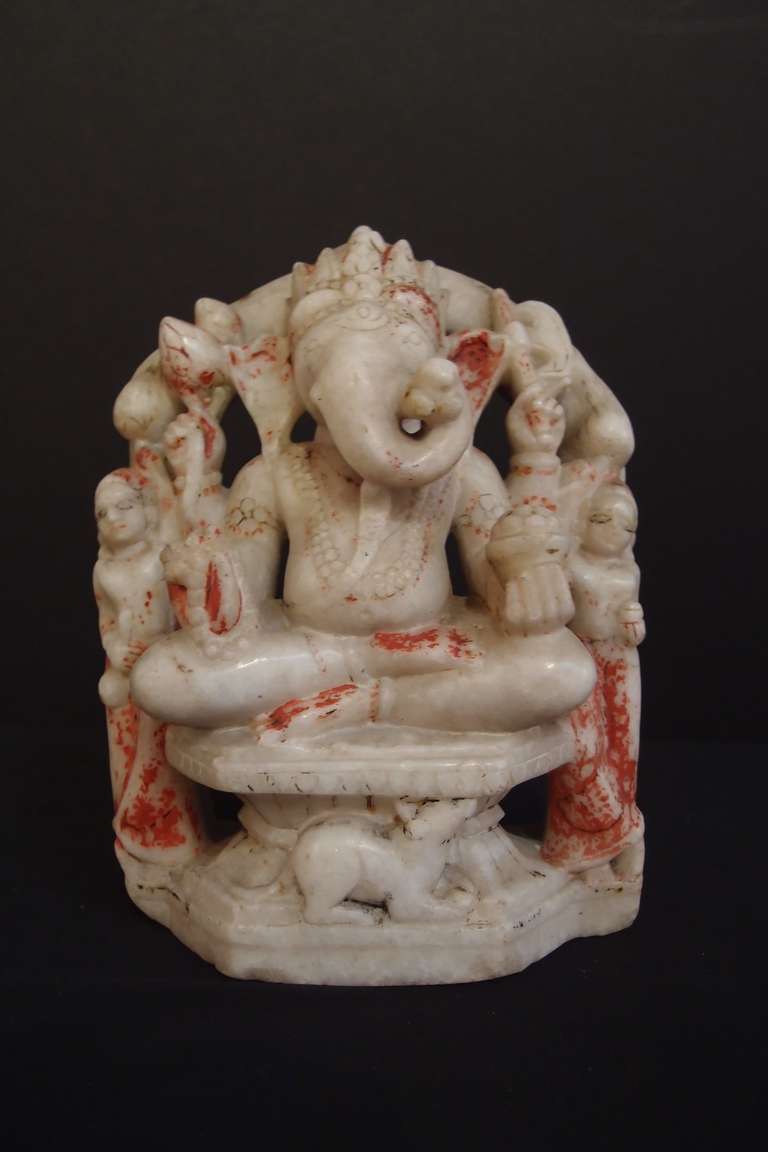 Ganesh, the ever popular Hindu elephant headed god, known as the remover of obstacles, is portrayed here in his four armed form holding a pot of sweetmeats, a mala, an axe and lotus buds. On his forehead a crescent moon under a third eye can be