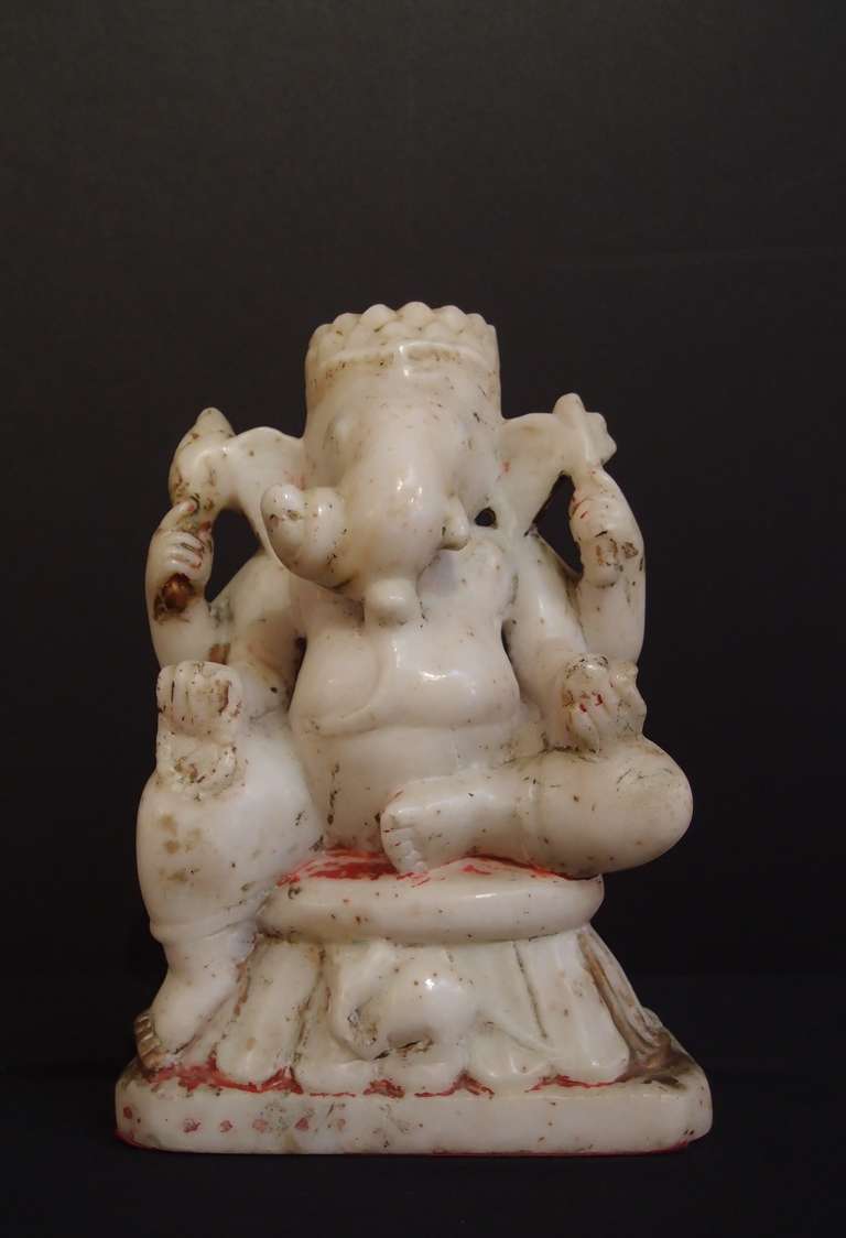 Ganesh, the ever popular Hindu elephant headed god, known as the remover of obstacles, is portrayed here seated upon a lotus throne in the royal ease position, one leg hanging pendant, his vahana, the rat, under his feet. His four arms hold various
