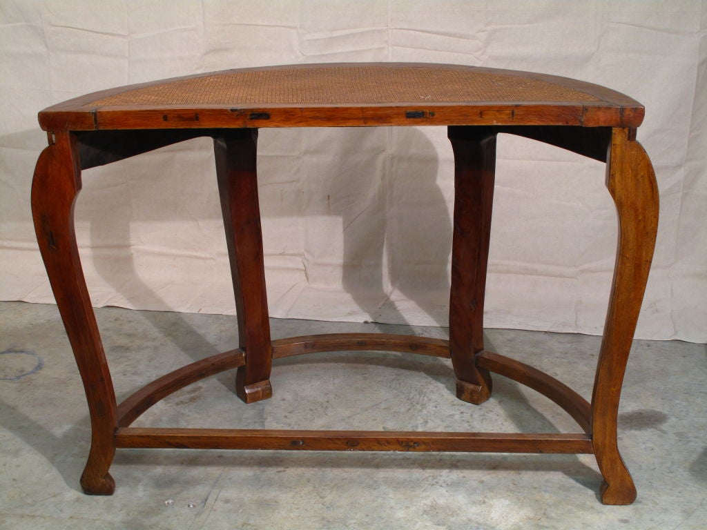 A simple and elegant Chinese demilune table in elmwood. Slight cabriole legs extend from a waisted apron with a decoration of low relief carved vines. The top features an inset woven rattan mat, 19th century.
