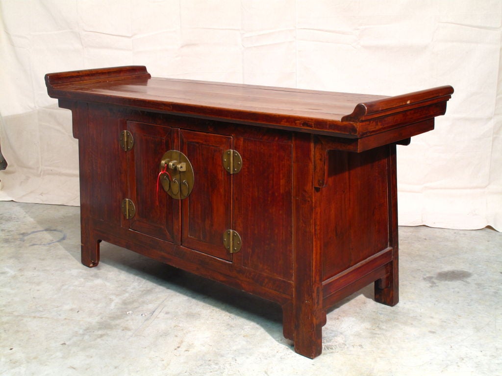 A solid Chinese sideboard or buffet of beautifully grained elmwood (jumu). The two doors open to reveal ample interior storage. The upturned ends of this piece suggest it may also have doubled as the family altar.