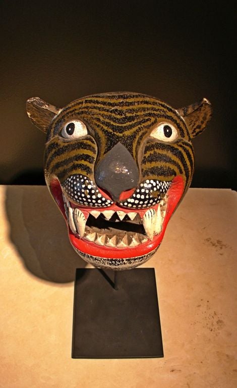 A wonderful carved and painted mask of a tiger, originally used in traditional Javanese dances (wayang topeng). He stares alertly ahead, ears perked, mouth open and fangs bared. A painted leather tongue is attached to the interior of his mouth.