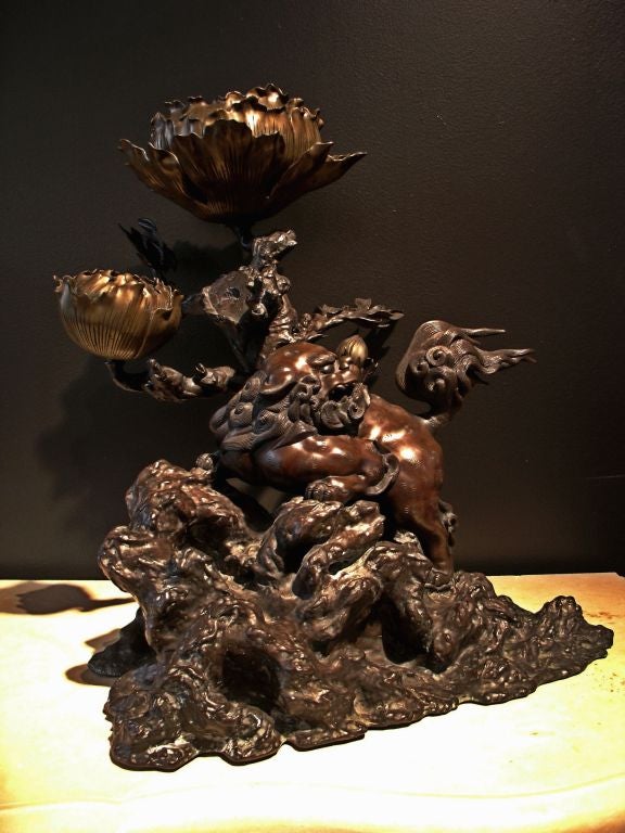 Commissioned for a temple, this large and impressive candle holder features a lively and alert shishi lion climbing up a rocky outcropping. His head is turned to look behind him, mouth slightly open. Pinwheel patterns simulating fur and representing