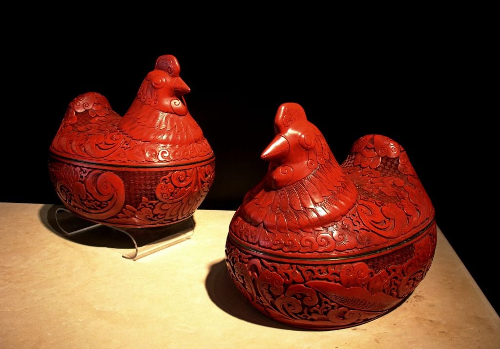 A finely carved pair of deep red cinnabar lacquer covered boxes in the form of roosting hens. <br />
<br />
The thick cinnabar lacquer is carved in meticulous and fluid detail. While the heads of the hens are realistically portrayed, the wings,