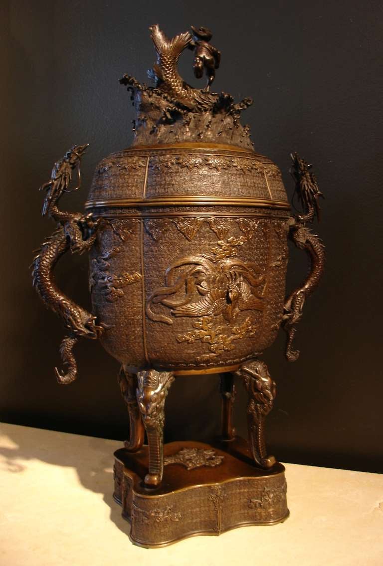 A large and impressive bronze covered koro (incense burner).

The quatrefoil body covered in an elaborate archaistic Chinese diaper pattern, with a central image of a phoenix in flight on either side. The handles crafted as two snaking dragons.