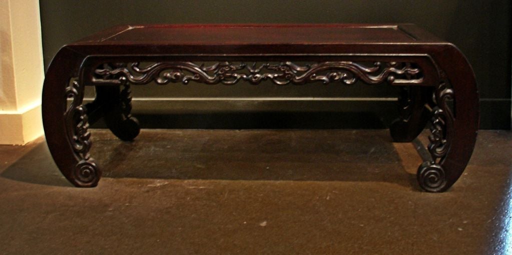A charming low kang table with scrolled legs. The apron carved with a pair of facing dragons, the pearl of wisdom between them. Additional dragons are carved along the interior curves of the legs.<br />
<br />
Carved from hongmu (blackwood), a