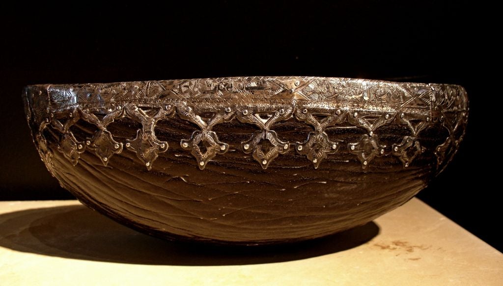 An exquisite kashkul (begging bowl) used by a Dervish, a Sufic ascetic.
This kashkul has been created from the hollowed out hull of a Coco de Mer palm nut. A band of finely worked silver-damascened steel runs the entire length of the rim, with