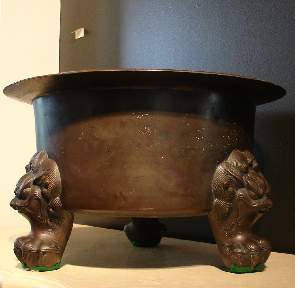 A large and impressive bronze censer or brazier. The wide, deep body rising to an everted rim, all supported on three feet cast as ferocious lion faces resting on clawed feet.

The bronze features a rich and warm chocolate-brown patina.