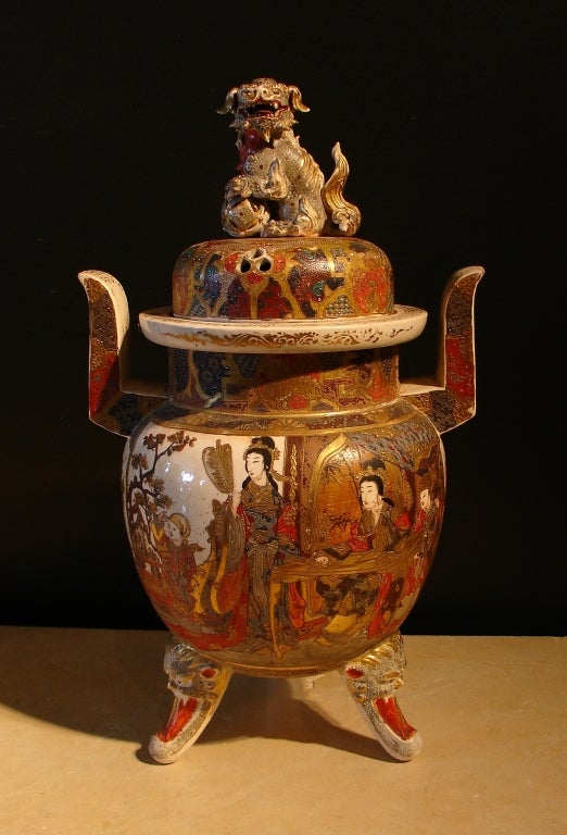 A Satsuma covered koro of globular form, set on tripod feet in the shape of lion heads with tongues extended, two large handles, and a pierced cover with a shishi dog finial.

Decorated all over with finely painted enamels to depict scenes of