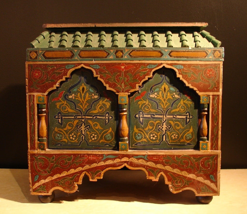 A highly decorative wooden storage chest in the Mudejar style, blending Islamic Moorish and Western European elements. The highly architectural design features columns, arches,  muqarnas, and a tiled roof. The polychrome design of arabesques with a
