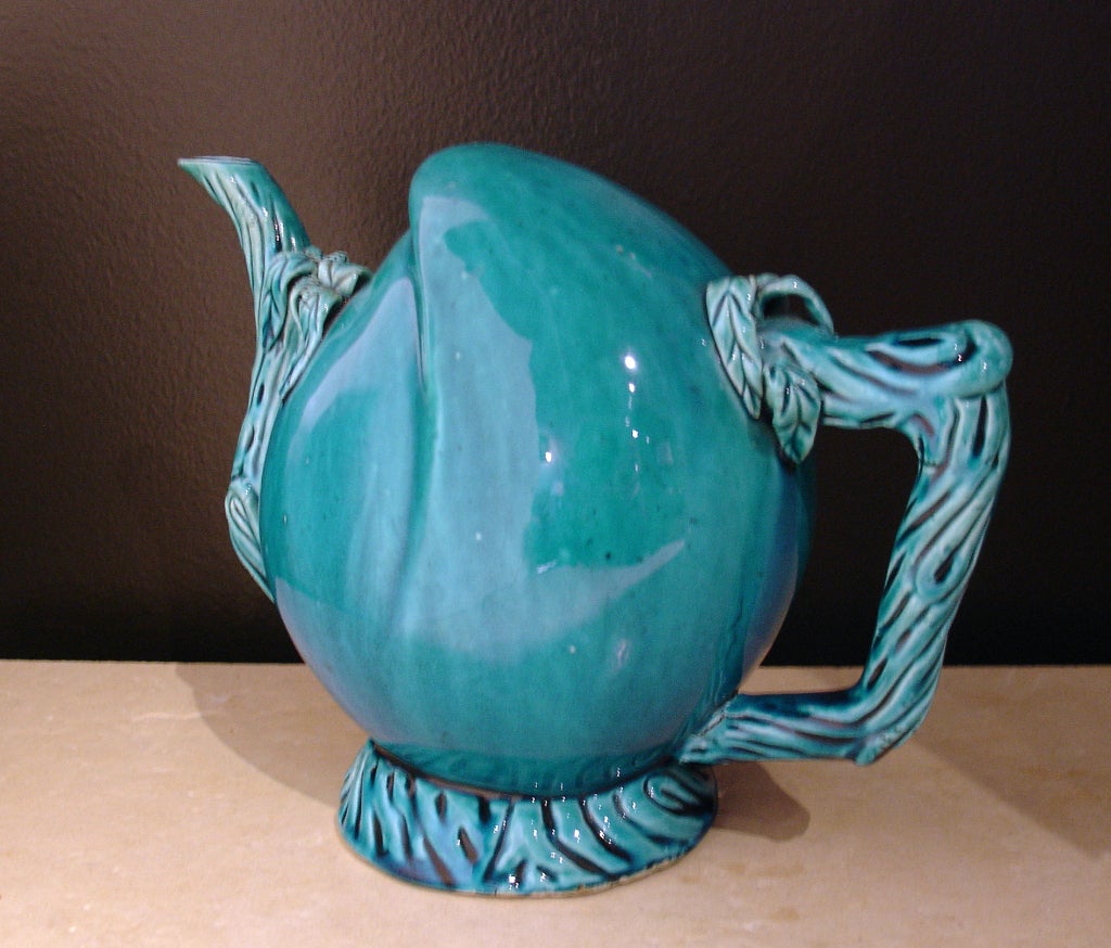 A Cadogan wine or tea pot shaped as a peach, with the handle and spout molded as intertwining branches. The entire pot covered in an intense turquoise glaze.