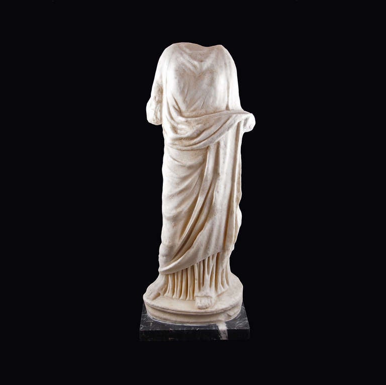 Beautifully carved from a lustrous white marble and displaying the gorgeous drapery Roman statuary is renowned for, this graceful lady stands comfortably on a rounded plinth with her weight resting on her left leg, right knee slightly bent. The