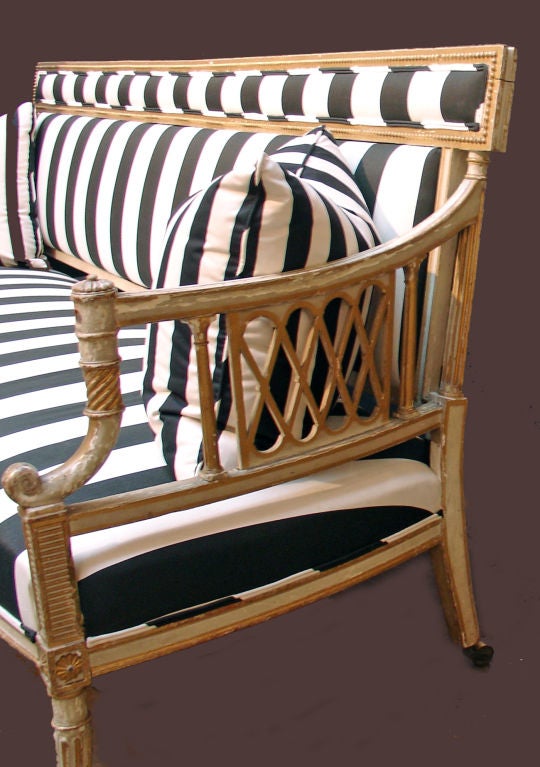 A striking 18th century George III canape on metal casters. Grey painted and parcel gilt frame, with black and white striped cotton upholstery, along with two matching pillows.