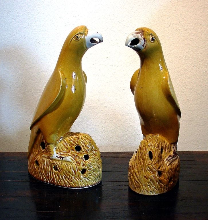 A fine pair of molded, yellow glazed porcelain parrots. Made for the export market, they are perched on naturalistic rock formations, with beaks open, and heads slightly turned to one side.