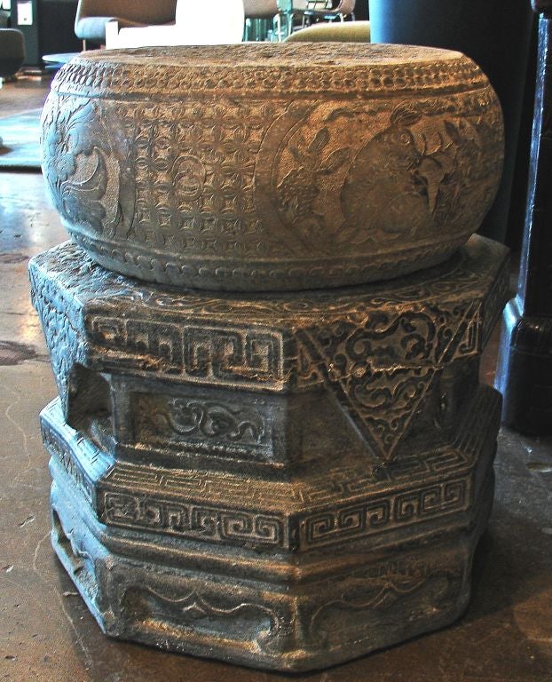 A pair of intricately carved stone garden stools or tables in two parts. The top carved as a drum (complete with carved nails) featuring animal and floral cartouches surrounded by a carved design field of either leaves or double vajras. The base