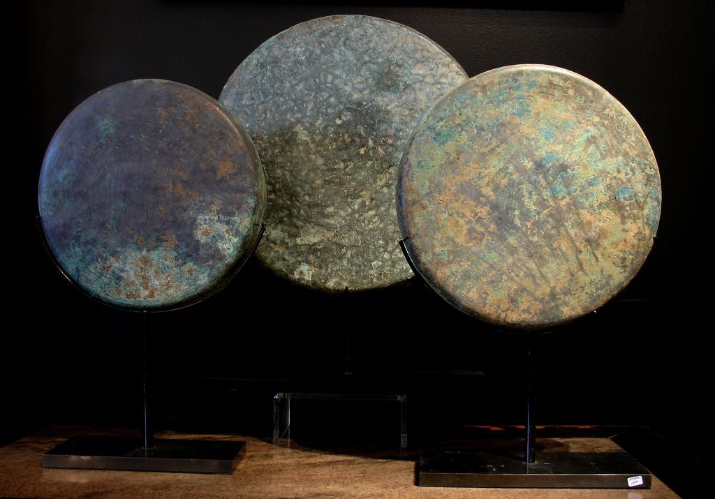 An assembled collection of bronze implements consisting of one tray and one gong, mounted on custom metal stands.<br />
<br />
All three have a beautiful patina of verdigris. The gong also has a wonderful textured surface from being struck.<br