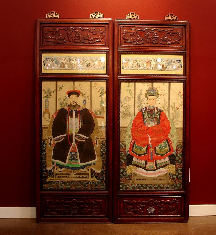 A pair of hand painted ancestor portraits in carved rosewood frames, with embroidery accents.<br />
<br />
The portraits are early 20th century portrayals of members of the Qing Dynasty Imperial court in their full regalia, complete with elements