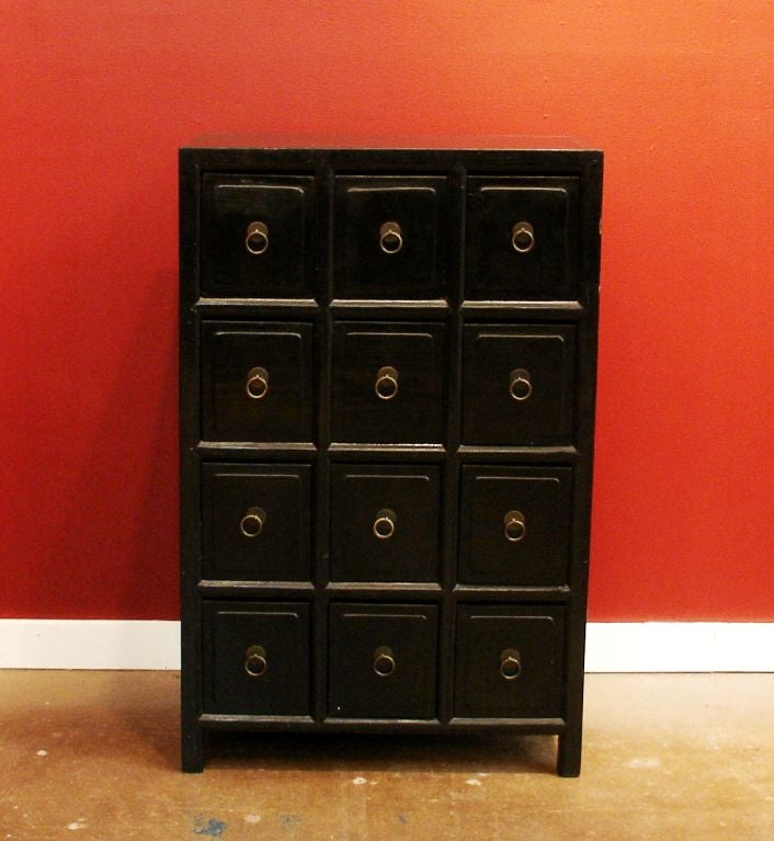 A small Chinese 12 drawer apothecary chest with original black lacquer finish and original brass hardware.