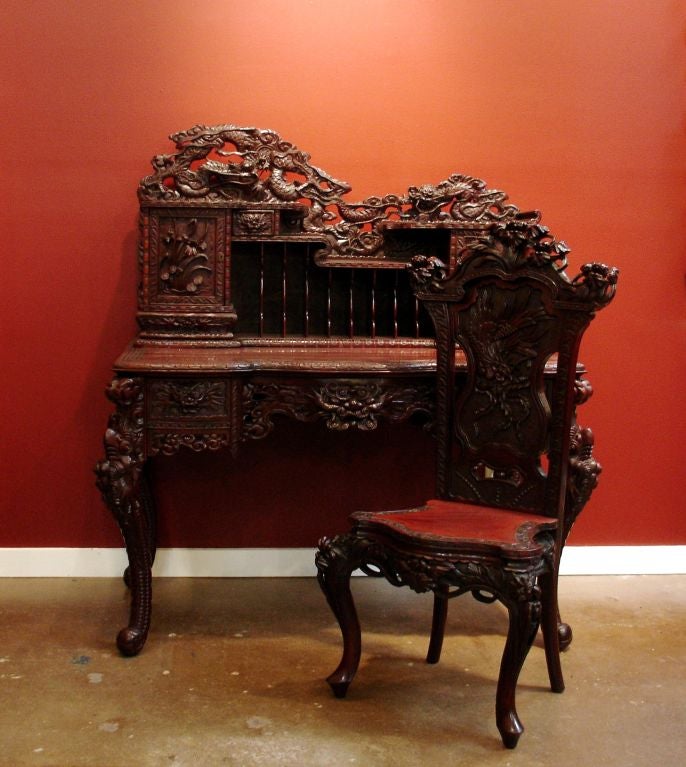 A heavily and well carved Japanese export desk and chair. <br />
<br />
The desk features two drawers with dragon head pulls, a dragon head apron, and dragon-form legs. <br />
<br />
The detachable hutch has a letter and file organizer, two