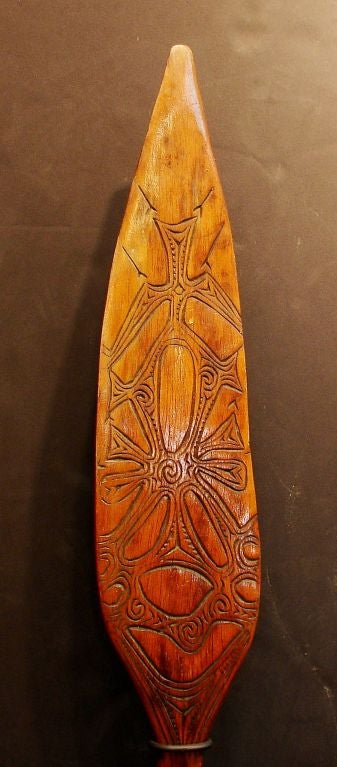 Based on canoe paddles, these are most likely ceremonial dance paddles.
Two similar ones from the Humboldt Bay/Lake Sentani area, Irian Jaya, with carved abstract zoomorphic bird forms on both sides, later varnished. The other more slender and less