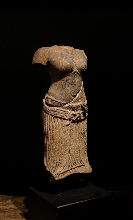 Although fragmentary and broken, this sculpture still exudes the quiet, sensual spirituality found in the best sculpture of the Baphuon. <br />
<br />
This unidentified female divinity wears a pleated sampot tied to accentuate her graceful hips,