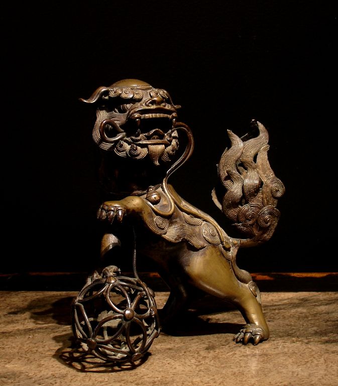 A Chinese censer in the form of a whimsical foo dog or lion.



Well cast. He stands nearly upright on his back paws, one forepaw raised, the other balanced on an openwork ball. He holds a streaming ribbon in his mouth.