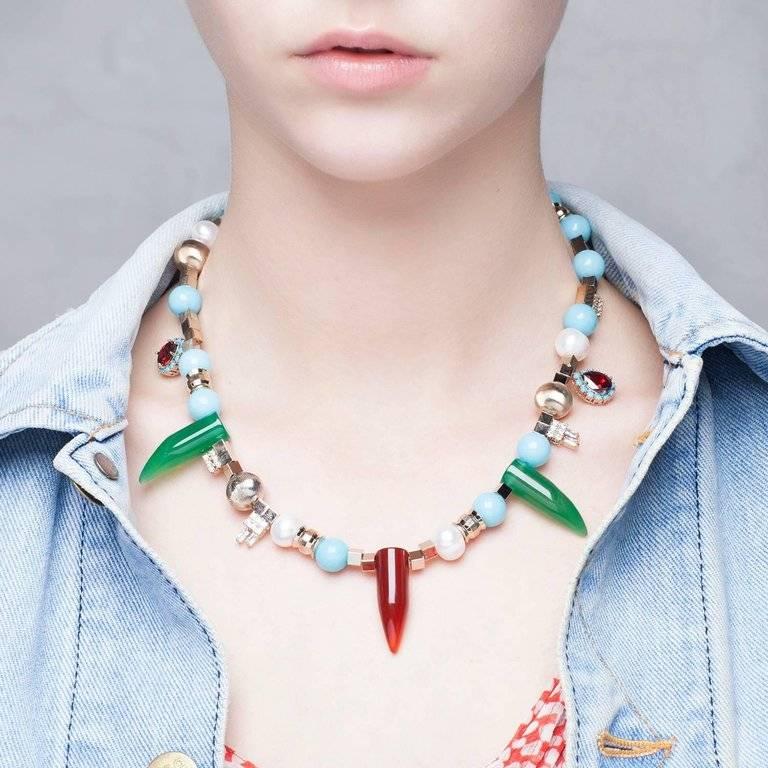 It's all about Iosselliani’s love for mixing shapes and different materials. This beaded necklace alternates freshwater pearls to hose jade and gilded brass beads. Embellished with chili-shaped horns in green and red agate, this piece allows you to