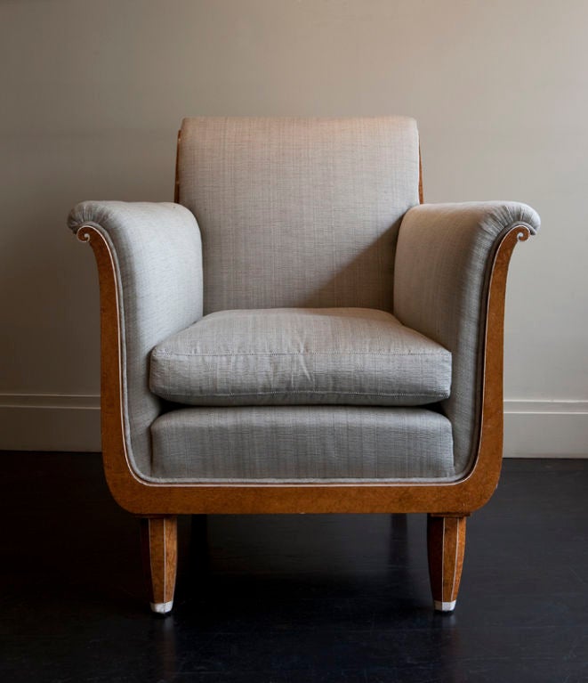 A pair of armchairs made out of amboyna wood with ivory details, upholstered in grey fabric.