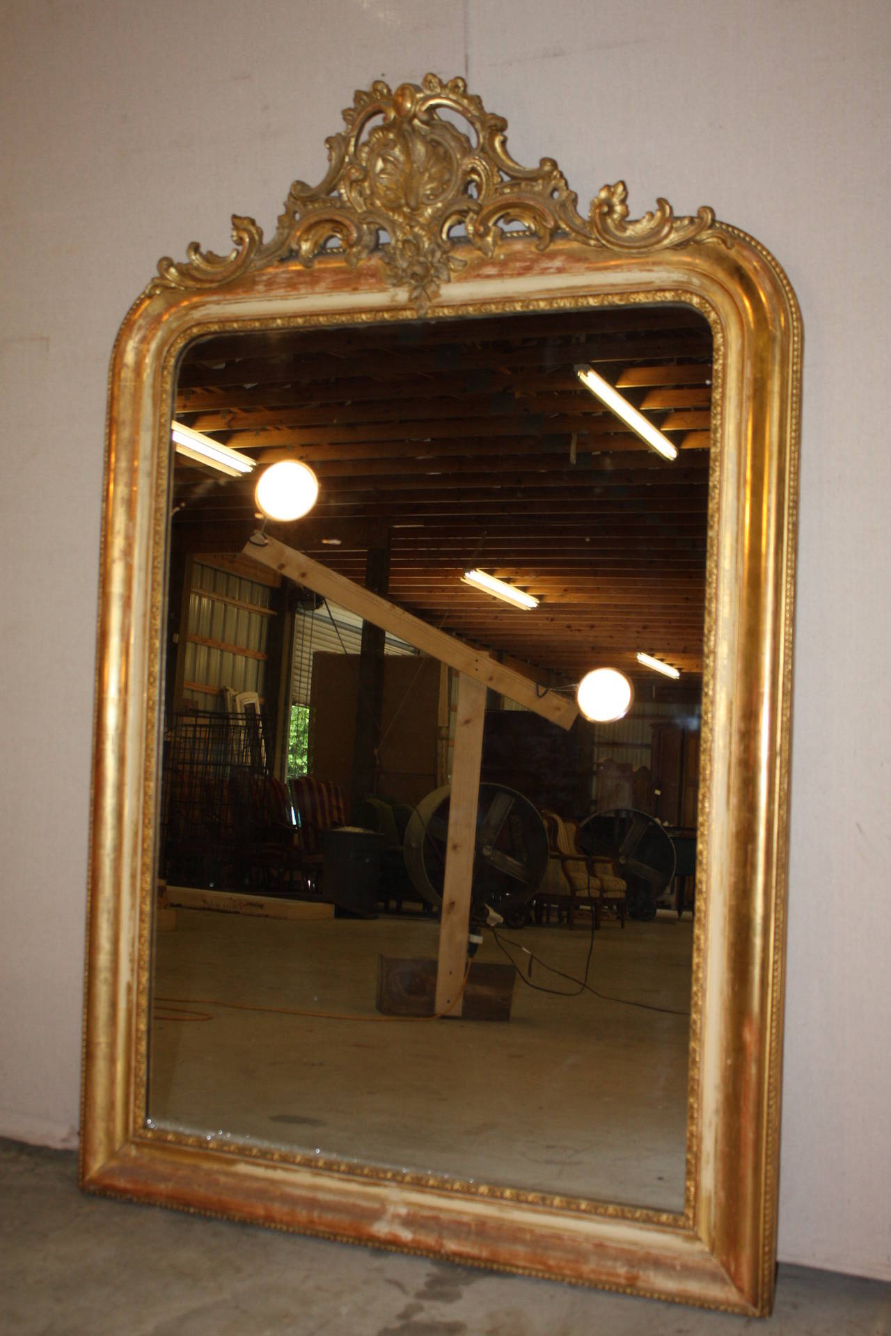 This is a very nice French gilded mirror with a Cartouche.  The glass is original to the mirror and shows some age but not to the point that the reflection is diminished.