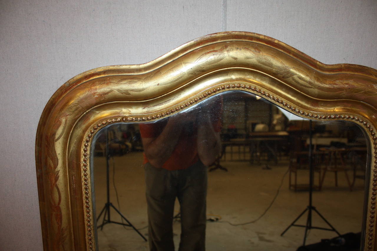 This is a very nice French Louis Philippe mirror with a serpentine top.  The shape is very attractive and rather rare.  Louis Philippe mirrors have either geometric patterns or floral patterns etched into the frames.  This one has a floral pattern. 