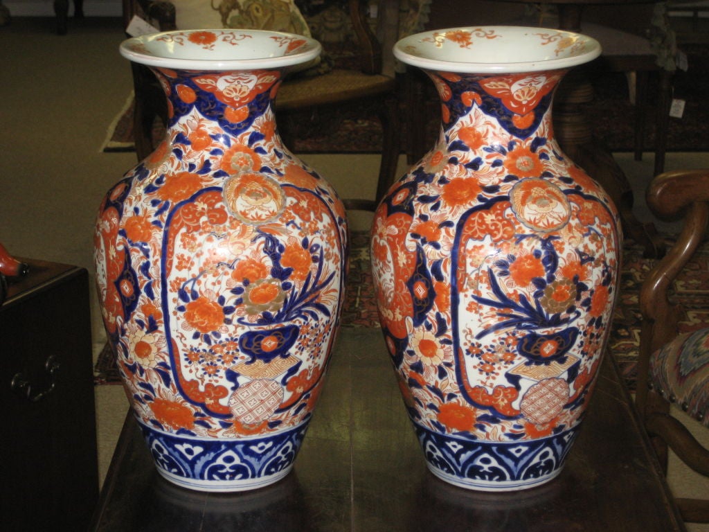 Pair of Japanese Imari vases from the late 1800s. Both vases are decorated with the traditional panels of urns filled with chrysanthemums in polychrome under glaze colors of blue, iron red with gilding.