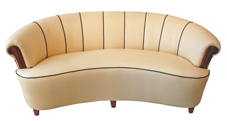 Curvacious sofa with legs and armrests in walnut upholstered in creme coloured Italian leather with a comfortable sprung seat.
