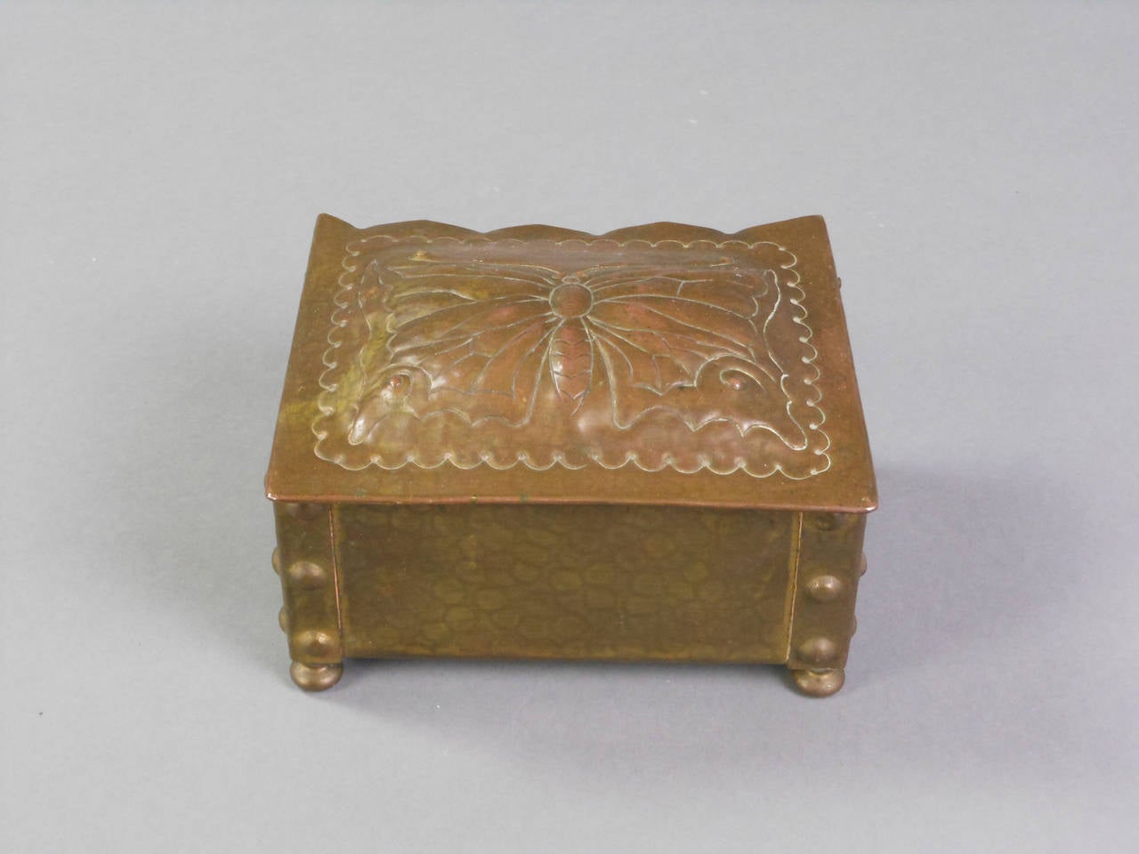 This patinated brass Swiss box has a hinged top with a wonderful butterfly in repousse. The hammered box is studded at the corners and has a wood-lined interior and stands on four bun feet. Stamped on the bottom: S. Canevascin Locarno.