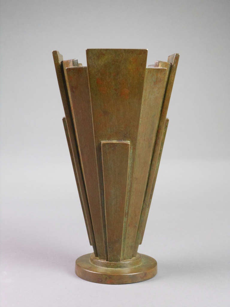 The green and brown patinated bronze vase is made of rectangular tapering layered panels on a stepped circular base. Marked made in Japan.