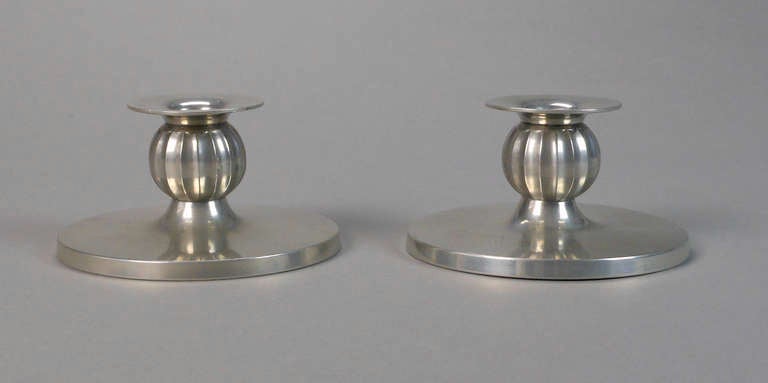Each with a fluted sphere surmounted by a circular candleholder and above a conforming base