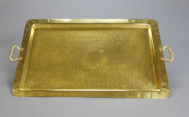The rectangular hammered brass tray has an outflaring rim fitted with rope twist handles.