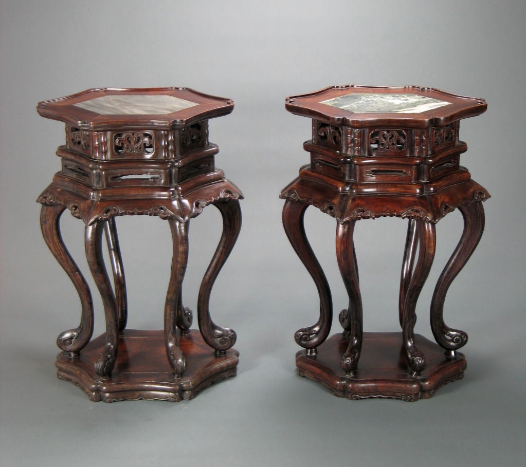 The two tables have a shaped lozenge top with scroll border and conforming inset marble and a pierced two tier frieze and foliate apron and border. Each table has six cabriole legs ending in scroll feet, on a lozenge base. Late Qing Dynasty.