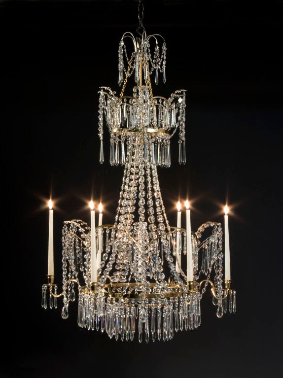 The two-tiered corona fitted with arches hung with swags and faceted drops, the central cascade of graduated strands and feather sprays, the principal tier fitted with six S-shape arms supporting urn form candleholders alternating with arches