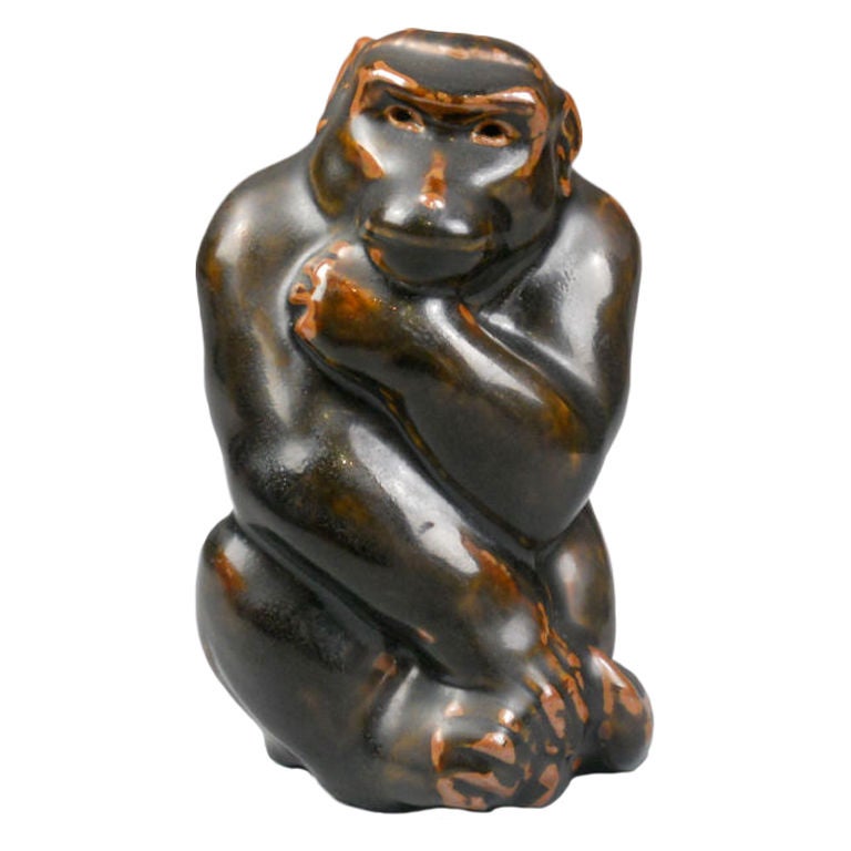 The monkey is seated with arms held against its body and has a dark brown glaze with highlights. It was made by Knud Kyhn for Royal Copenhagen and is marked on the bottom 20133 over the painted Royal Copenhagen symbol of three waves.