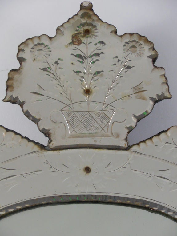 This mid-18th century mirror comes from Northern Europe. The divided arched mirror plate has a beveled glass border with etched scrolling foliate decoration. The crest has a floral basket and the corners have cartouche mounts.